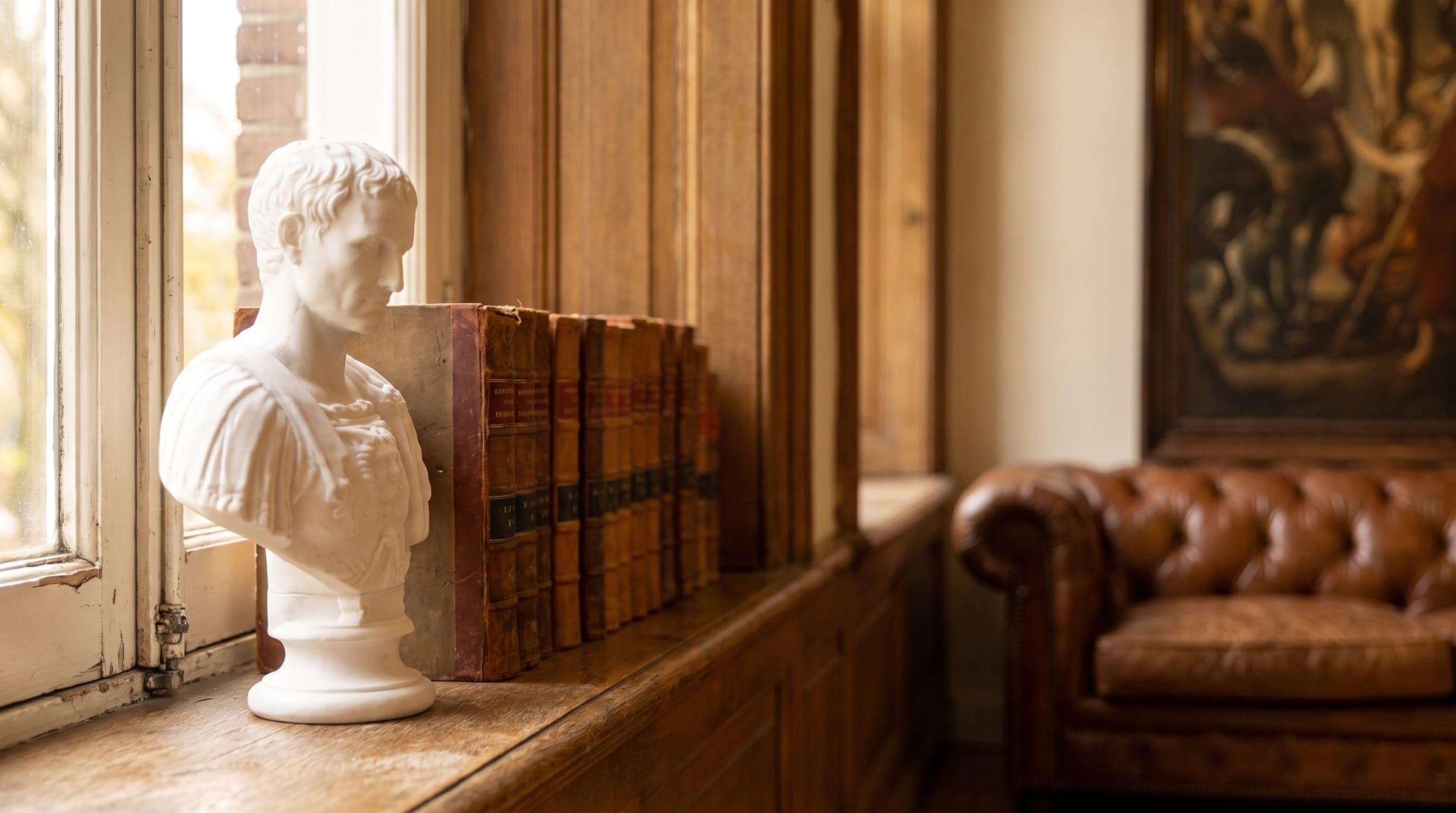 Klassieke marmeren buste naast oude wetboeken op een vensterbank